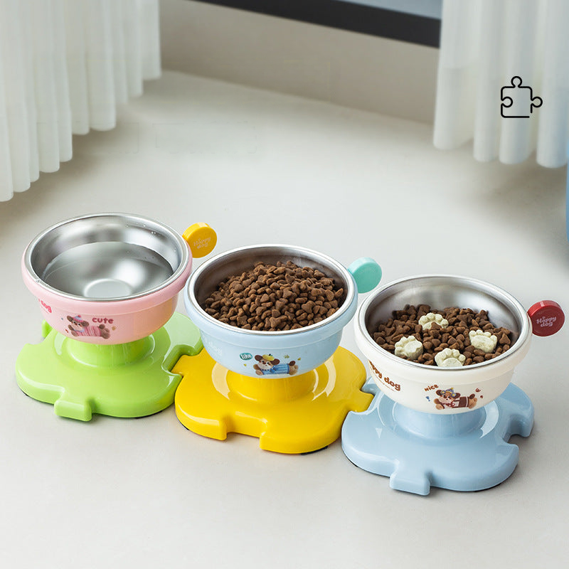 Three elevated dog bowls with jigsaw-shaped bases on a wooden floor beside a window.