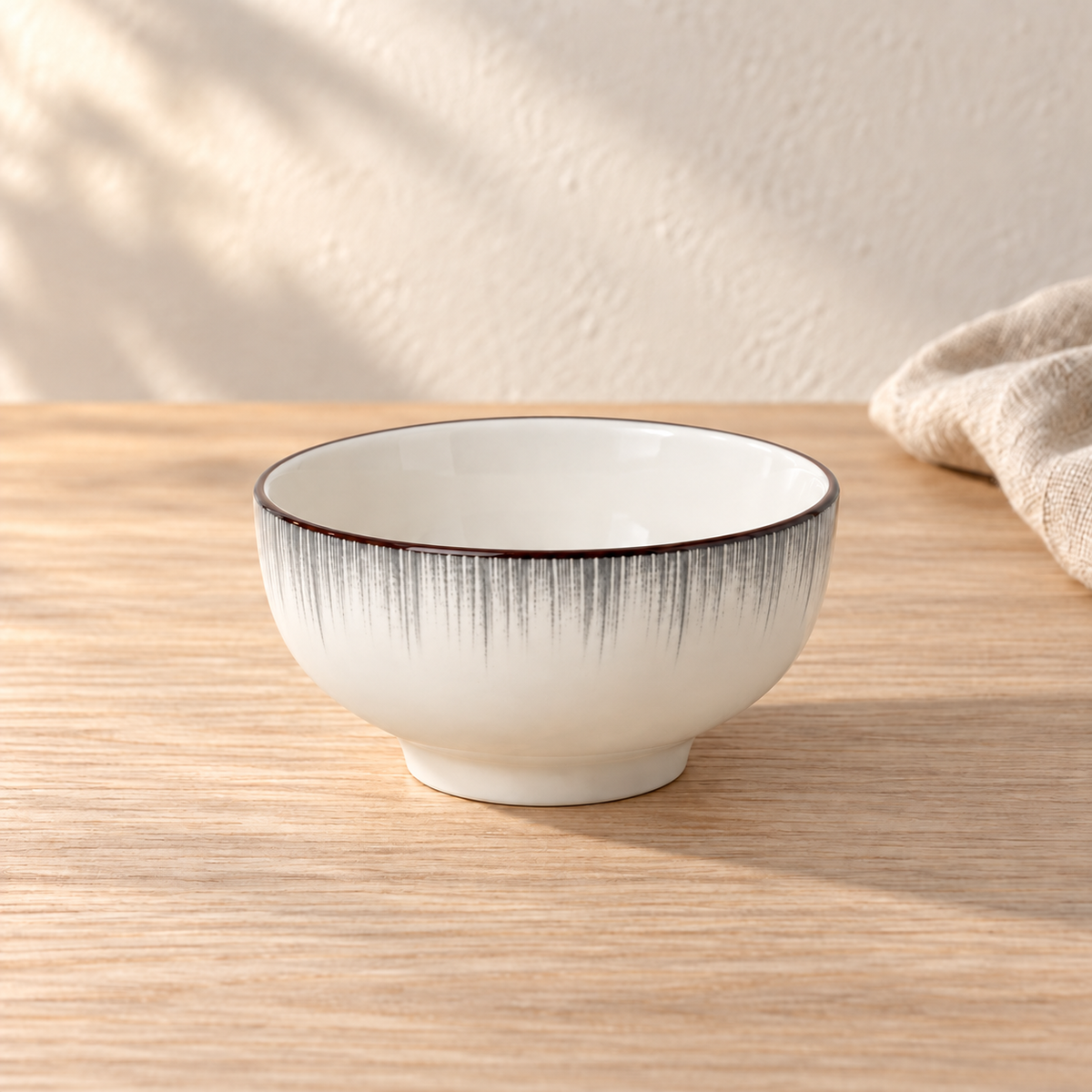 A pale celadon 6 inch noodle bowl with fine grey brush strokes below the rim, on a light wood table in afternoon light.