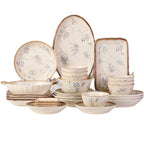 The cream set arranged on a white background: round and oval plates with a blue and brown floral spray, a rectangular tray, a two-handled serving bowl, stacked rice bowls and shallow dishes.