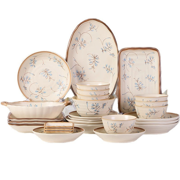 The cream set arranged on a white background: round and oval plates with a blue and brown floral spray, a rectangular tray, a two-handled serving bowl, stacked rice bowls and shallow dishes.