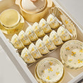 The cream set with small yellow flowers laid out in an open kitchen drawer: rows of rice bowls in a rack, stacked plates, a lidded casserole and a handled serving tray.