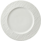 A wide white dinner plate on a white background, smooth centre well and a broad rim with a rough stone-like texture.