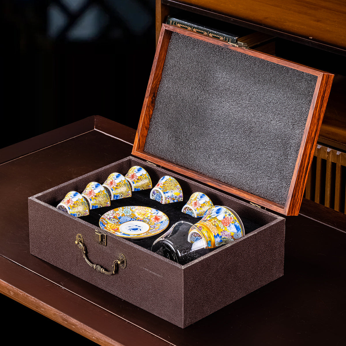 The cups and saucer nested in a lined presentation case with the hinged wooden lid open.
