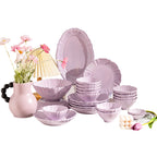The lilac set arranged on a white background: a scallop-edged oval platter, a dinner plate, fluted bowls in several sizes and small dishes, all with a faint floral relief.