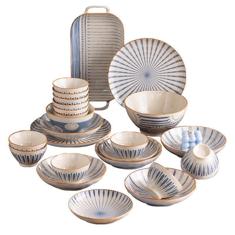 The blue and cream set arranged on a white background: a handled rectangular tray, a plate with radiating blue stripes, bowls of several sizes, shallow dishes and a small lidded pot.