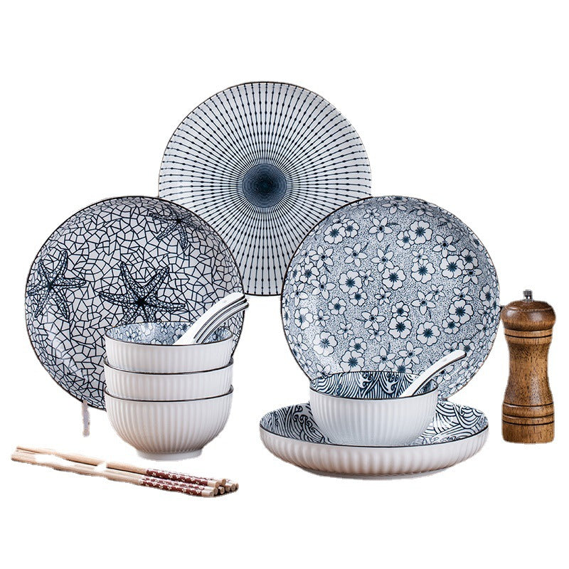 Five mixed blue and white patterned plates and bowls arranged on a white background with spoons, chopsticks and a wooden pepper grinder.