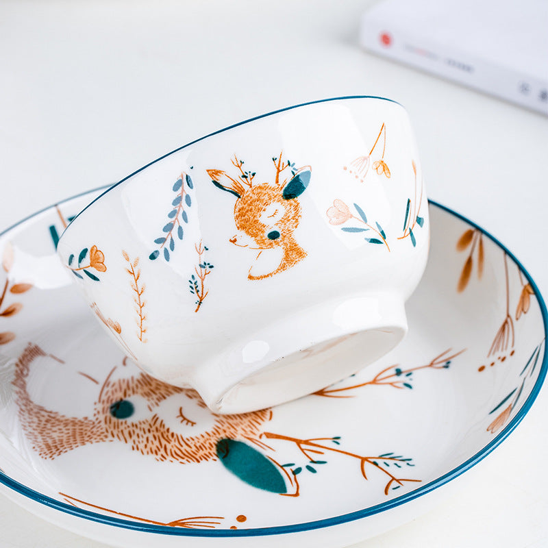 A bowl printed with a fawn tipped against a matching plate showing a rabbit, both finished with a dark teal rim.