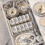The set stored in an open kitchen drawer: two rows of bowls in a rack, stacked plates, an oval platter and serving spoons.