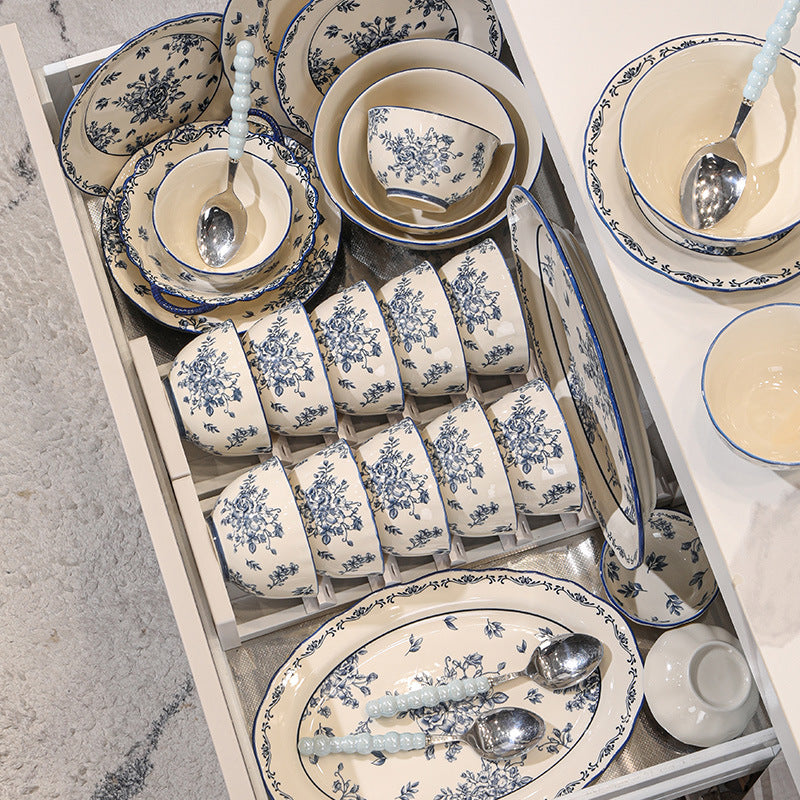 The set stored in an open kitchen drawer: two rows of bowls in a rack, stacked plates, an oval platter and serving spoons.