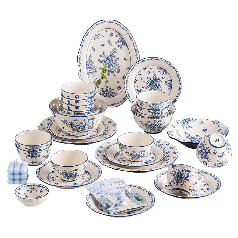 The blue and white set arranged on a white background: an oval platter, plates and bowls printed with small blue flowers, a lidded soup bowl and shallow dishes.