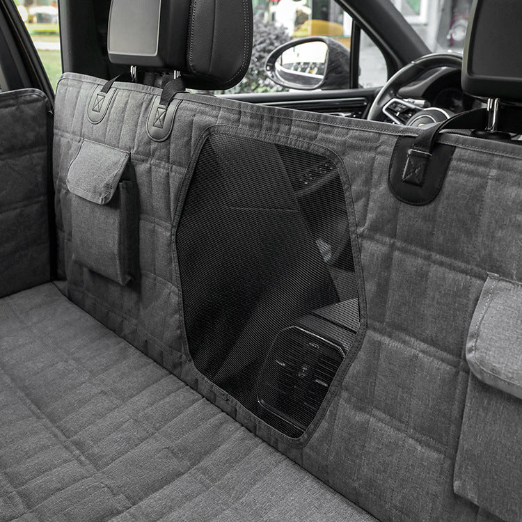 Light gray dog back seat cover with mesh window panel and side pockets inside a car