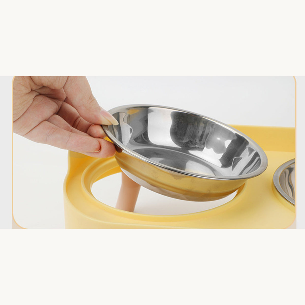 Hand lifting a stainless steel bowl out of the lemon yellow frame