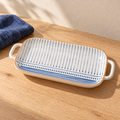 A long blue rhyme fish platter with a hand-painted blue motif, on an oak table with indigo linen.