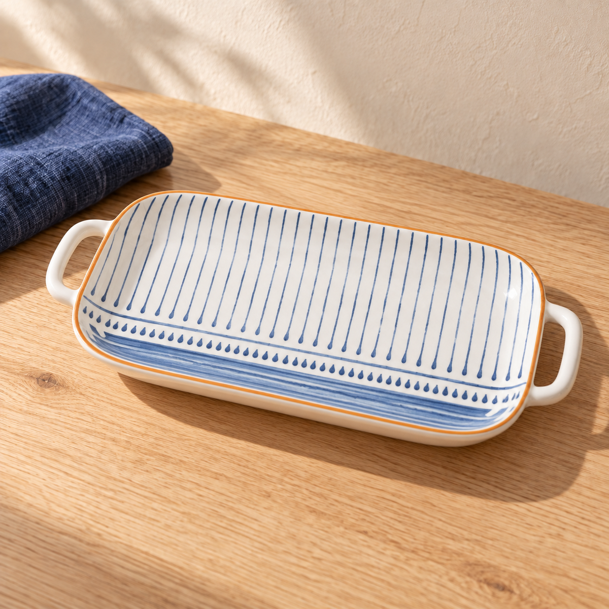 A long blue rhyme fish platter with a hand-painted blue motif, on an oak table with indigo linen.