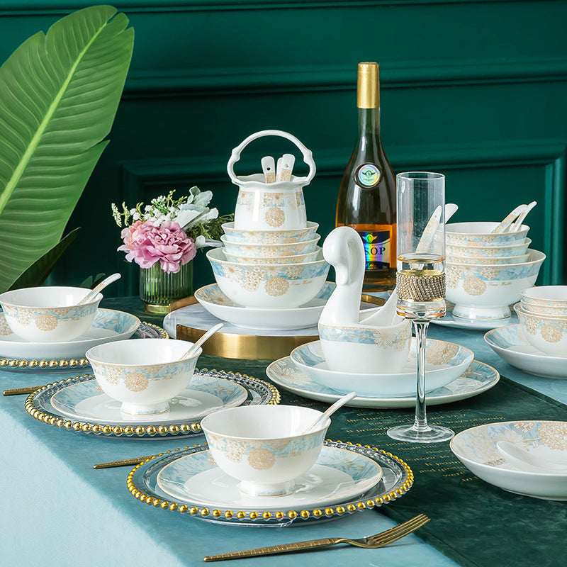 The set styled on a dining table with glassware, a swan serving piece and flowers