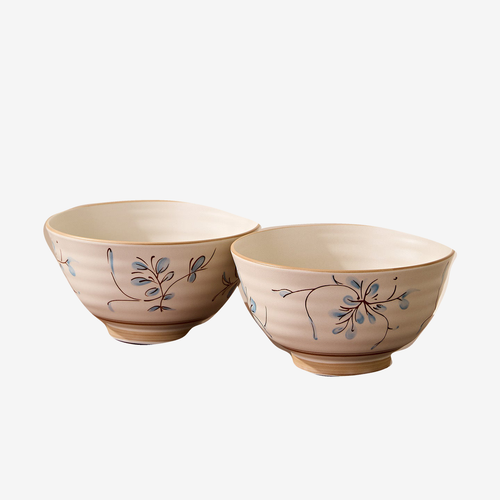 Two cream noodle bowls with a blue and brown sprig motif and a ribbed foot, shown together against a plain light background.