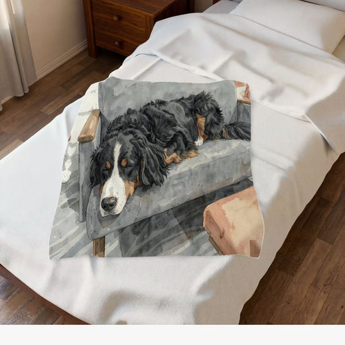 Velveteen plush blanket printed with an illustration of Waffle, our Bernese Mountain Dog, asleep on a grey armchair, spread over a made bed (edited photo)