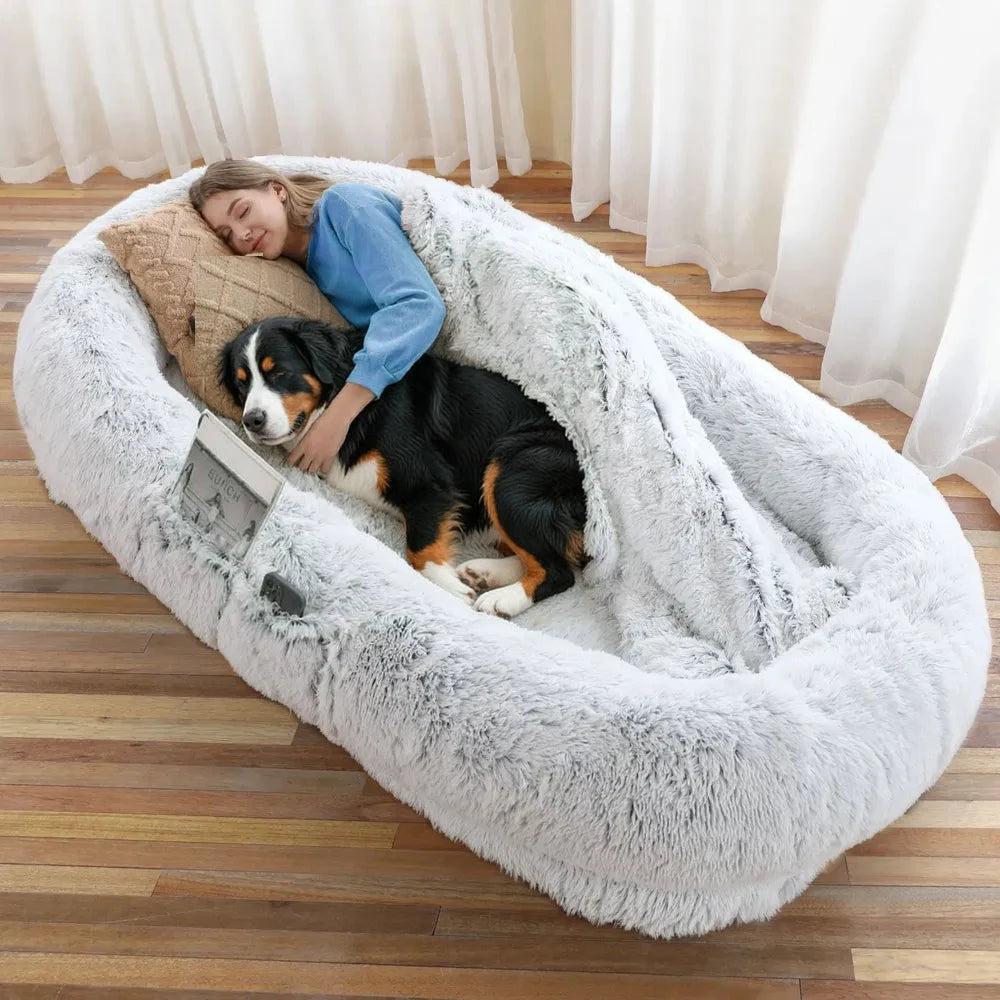 Woman sleeping with a Bernese mountain dog in a gray faux fur human dog bed