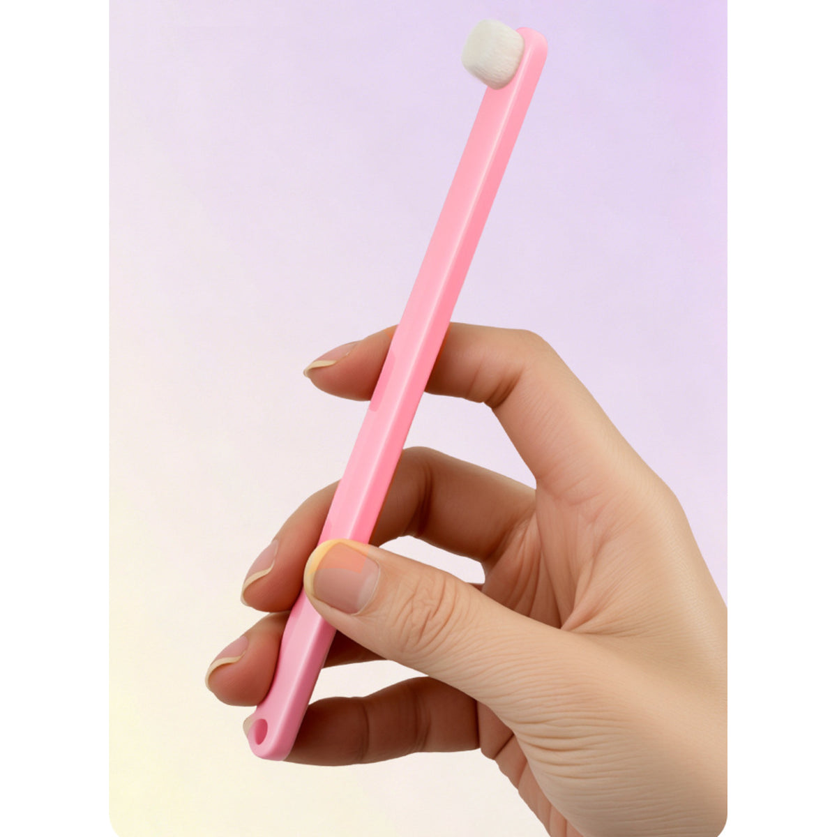 A hand holding the pink toothbrush, showing the handle length against the fingers