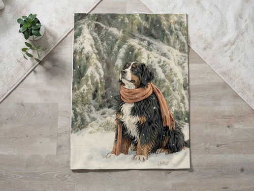 Example custom blanket on a wood floor: a watercolor portrait of a Bernese Mountain Dog in an orange scarf sitting in the snow, printed on a velveteen plush throw