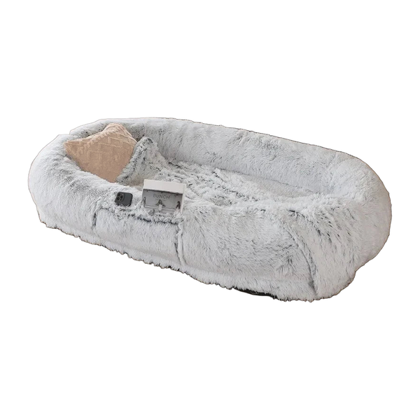 Grey faux fur human-size dog bed with a raised rim and pillow, white background