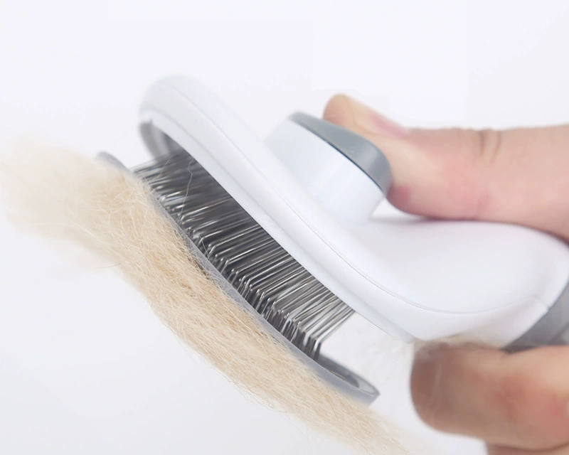 Hand pressing the release button on the self-cleaning slicker brush to push collected dog hair off the pins