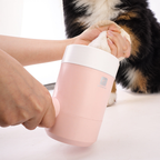 Pink paw washer cup held at the base while a Bernese mountain dog puppy has a paw washed