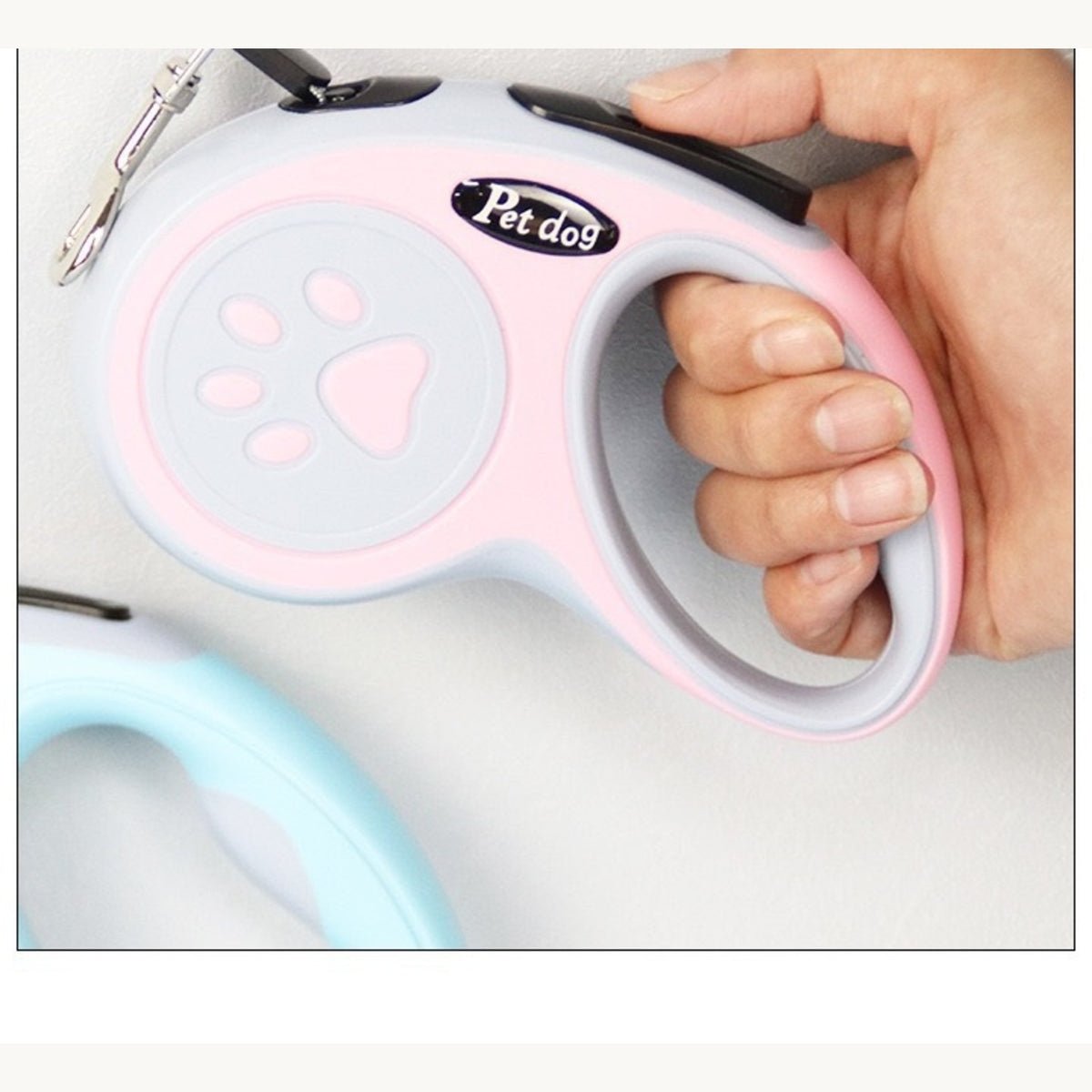 The retractable leash handle held in one hand, paw-print grip facing out