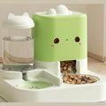 Green 2-in-1 gravity pet feeder: clear water bottle with a cat-ear lid on the left, mint-green dry-food hopper with a cat face on the right, both on one white base with a kibble bowl and a water dish