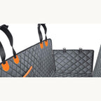 The quilted car seat cover laid out with its side flaps and orange buckle straps